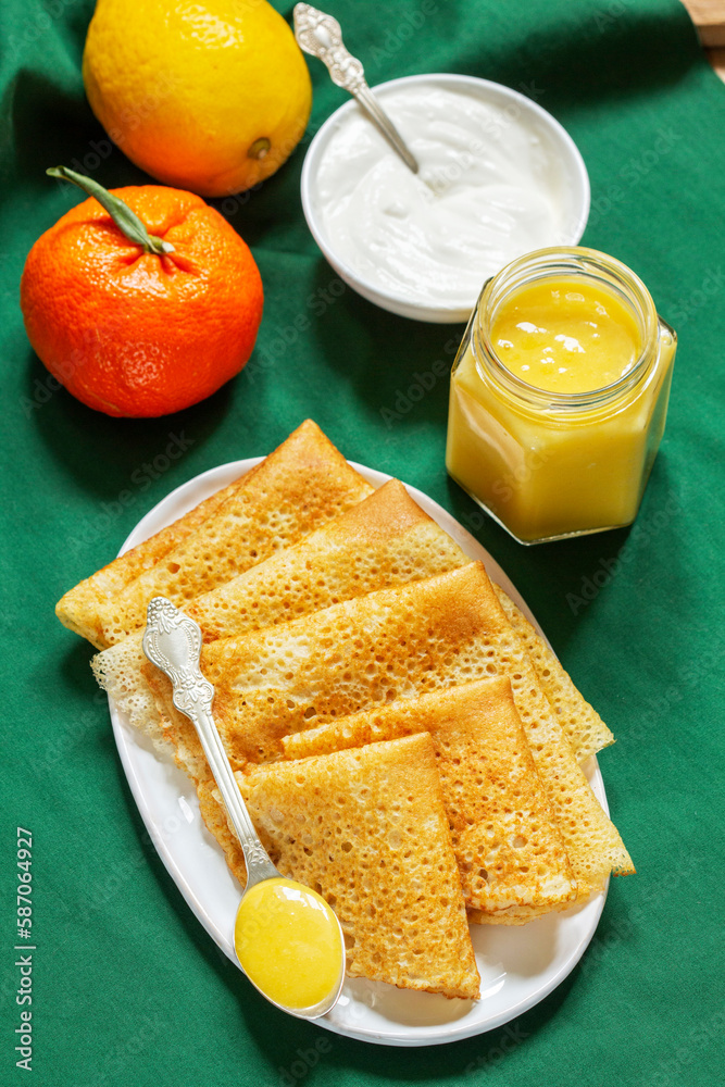 Pancakes served with fruit curd and sour cream, a traditional meal for Maslenitsa and Carnival.