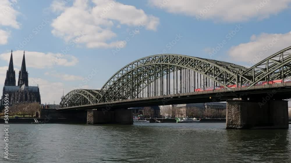 Panoramic view of Cologne Cathedral and trains passing on Hohenzollern Bridge in Cologne, Germany Panoramic view of Cologne Cathedral and trains passing on Hohenzollern Bridge in Cologne, Germany