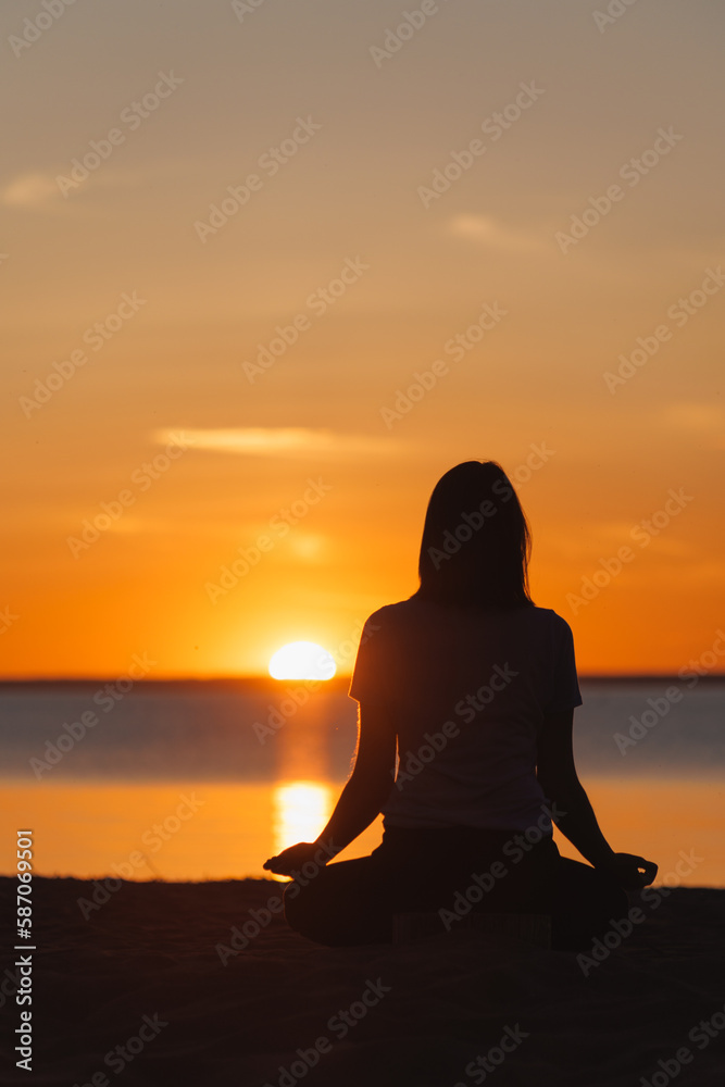 soft selective focus, yoga meditation, silhouette of woman at sunset in lotus position. health recreation and sports, outdoor training. poster.person is engaged in breathing practices. mental health
