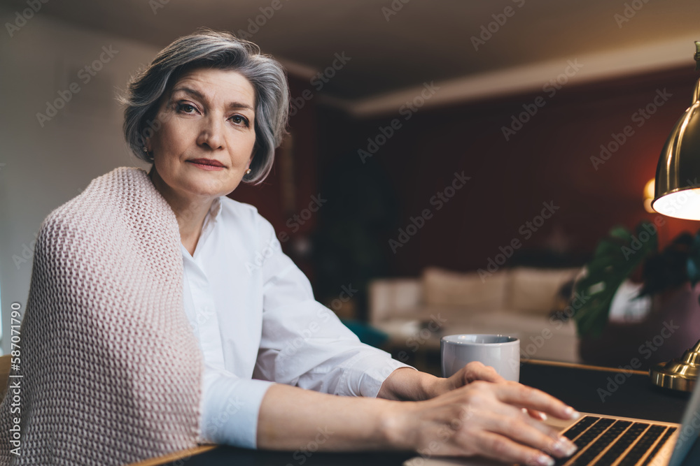 Determined woman with cup of coffee working on laptop Determined woman with cup of coffee working on laptop