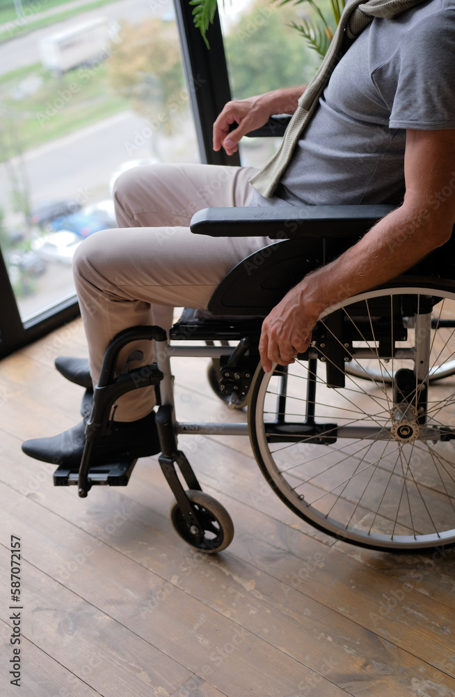 Close up view elderly male hand on rotary ring of self-propelled wheelchair. Concept of movement disorder loss of muscle function caused by age, senile disease, accident Close up view elderly male hand on rotary ring of self-propelled wheelchair. Concept of movement disorder loss of muscle function caused by age, senile disease, accident