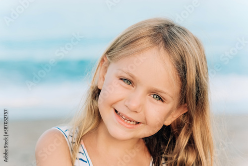 sunny summer day near the sea excited happy smiling face portrait adorable child toddler girl in blue dress © Maria