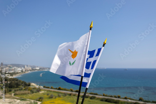 Cypriot and Greek flags waving in the wind in front of blue sea, sky and landscape