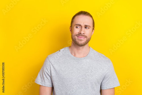 Photo of uncertain unsure man watching empty space banner poster weird proposition isolated on yellow color background