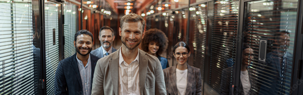 Group of happy, motivated business people standing together at office with their leader Group of happy, motivated business people standing together at office with their leader