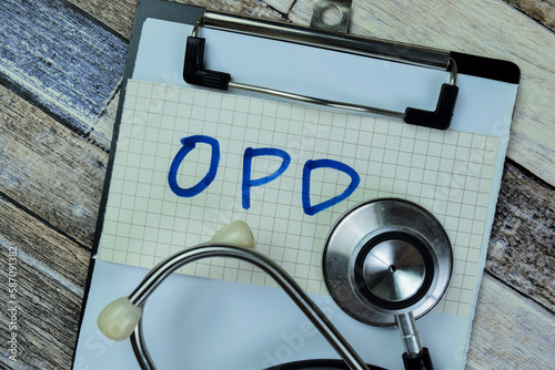 Concept of OPD write on sticky notes with stethoscope isolated on Wooden Table. photo