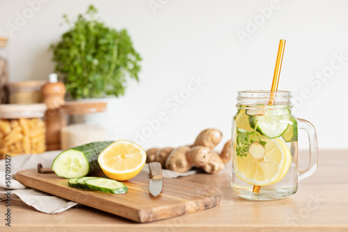 Infused water with cucumber, lemon and ginger in glass bottle on wooden table. Diet, detox, healthy eating, weight loss concept