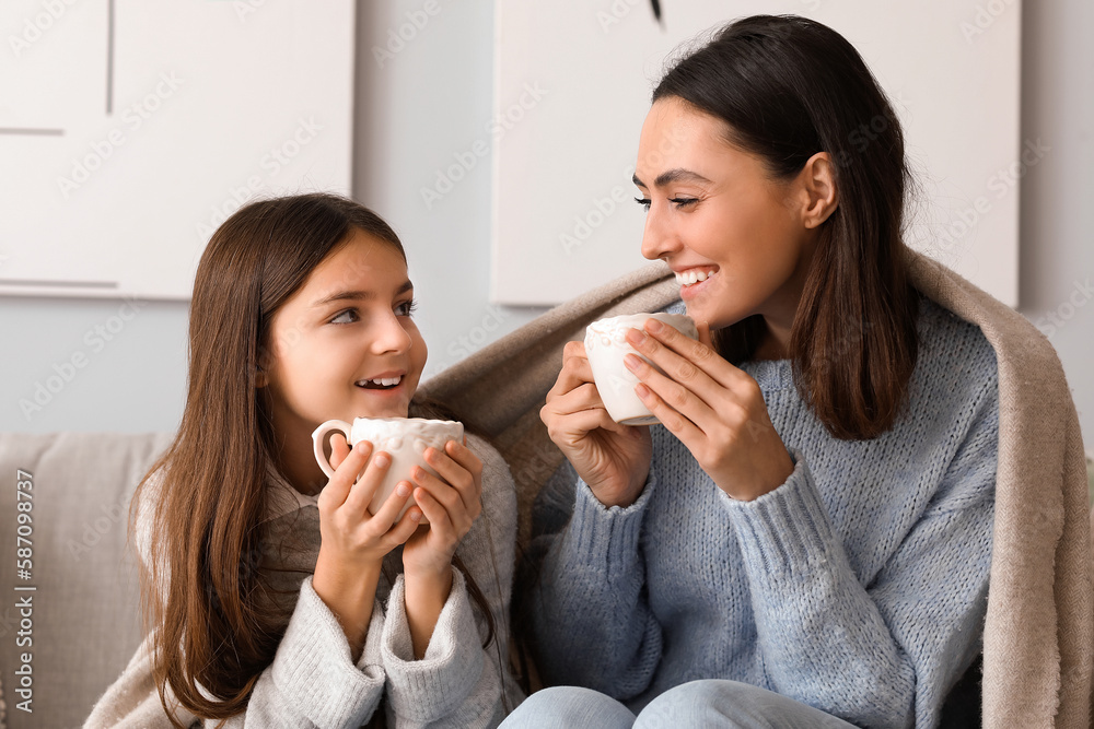 Little girl and her mother with cups of tea sitting at home Little girl and her mother with cups of tea sitting at home