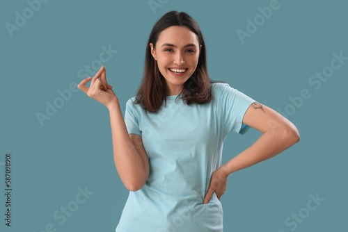 Young woman snapping fingers on blue background