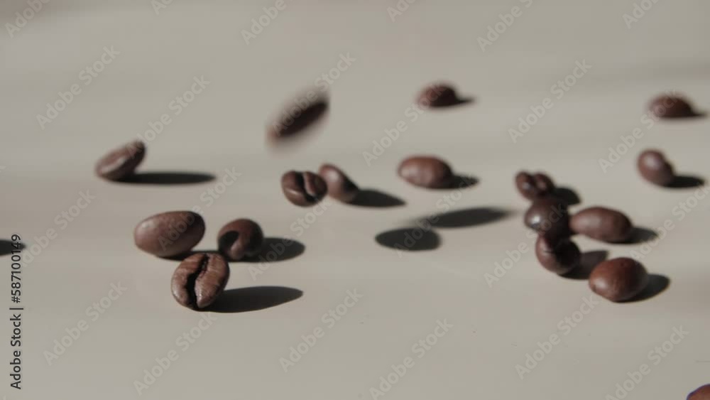 Coffee beans falling on a light surface. Roasted coffee beans falling on light surface. Coffee beans bouncing. Closeup. Slow motion. Coffee beans falling on a light surface. Roasted coffee beans falling on light surface. Coffee beans bouncing. Closeup. Slow motion.