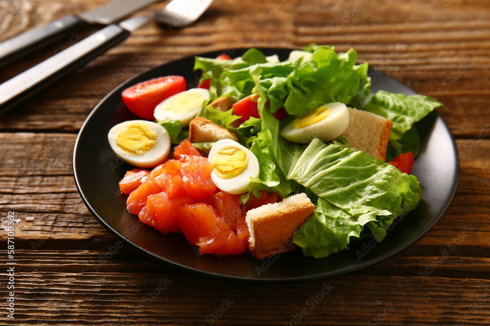 Plate of delicious salad with boiled eggs and salmon on brown wooden background Plate of delicious salad with boiled eggs and salmon on brown wooden background