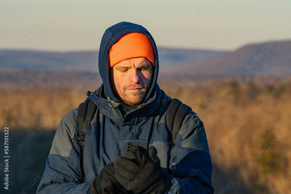 winter season hiker taking a selfie or looking at his phone, lifestyle  