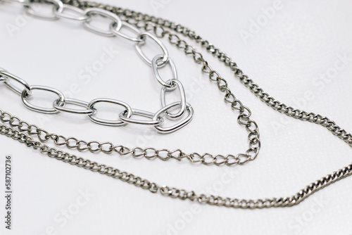 Different silver metal chains on a light background.