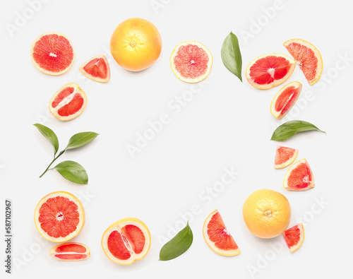 Frame made of juicy grapefruit pieces and plant leaves on white background