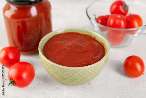 Bowl of tasty tomato paste on white grunge background