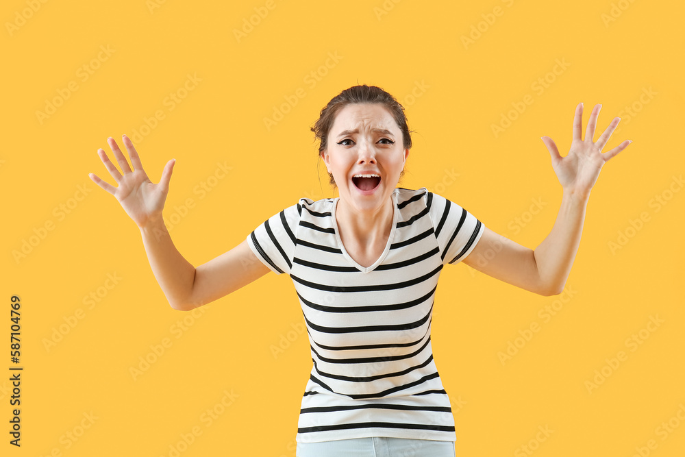 Naklejka premium Scared young woman on yellow background