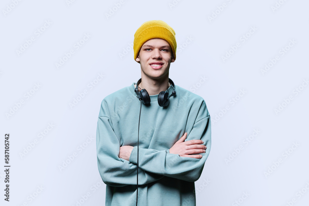 Young male in yellow cap sweatshirt with headphones on white background Young male in yellow cap sweatshirt with headphones on white background
