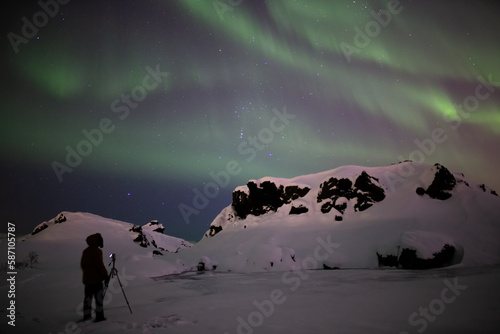Photographer looking at aurora borealis, winter Iceland © Arctic Mystic