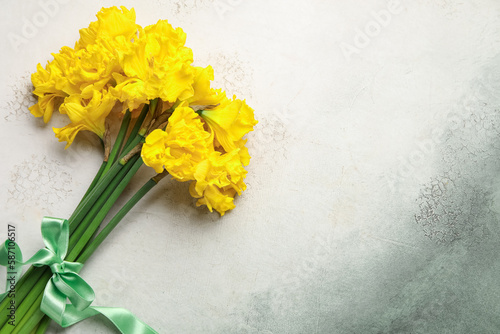 Beautiful narcissus flowers with green ribbon on color background
