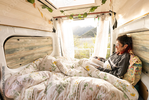 woman reading in the camper van, caravan, at sunset, book, woman smiling in nature