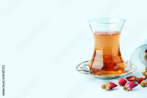 Glass of Turkish tea and dry roses on light blue background