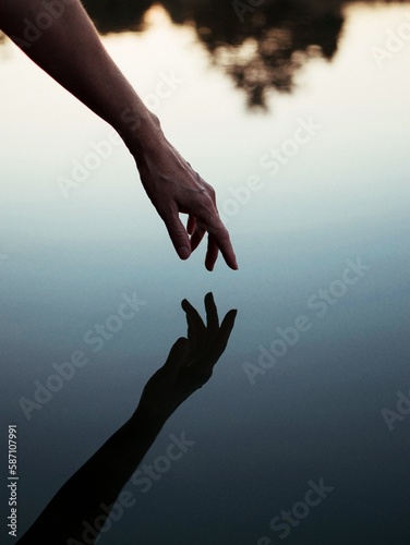 Person's hand approaching body of water with reflection photo