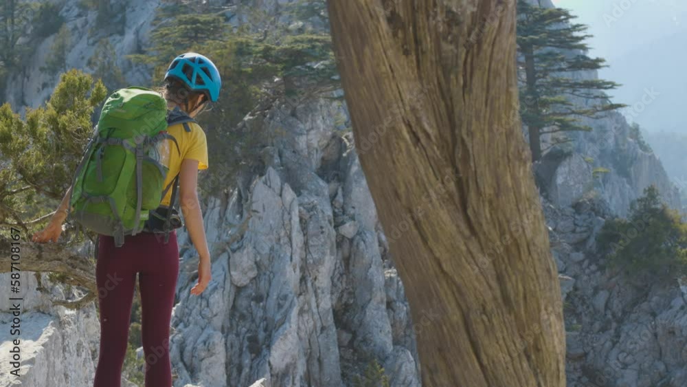 Woman climber with a backpack and a helmet in the mountains. A girl with a backpack walks along a mountain range. adventure and mountaineering concept. mountains of Turkey. Woman climber with a backpack and a helmet in the mountains. A girl with a backpack walks along a mountain range. adventure and mountaineering concept. mountains of Turkey.