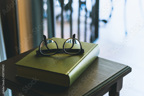 Framed eyeglasses on green book photo