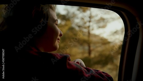 School age girl smiling carelessly and enjoying journey. Happy family travel concept. Child leaned out of car window smiling with pleasure