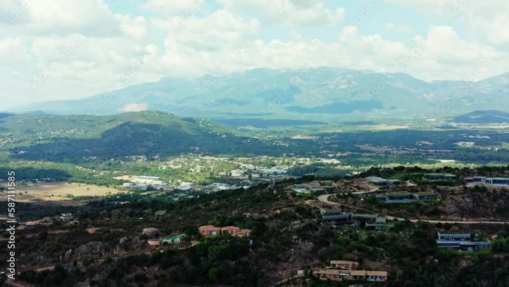 The aerial view of Corsica's countryside showcases a beautiful panorama of rolling hills, green valleys, and charming villas surrounded by trees and vegetation The aerial view of Corsica's countryside showcases a beautiful panorama of rolling hills, green valleys, and charming villas surrounded by trees and vegetation
