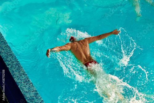 A male swimmer is training in the pool  a top view of a swimmer swimming along the track in the pool.