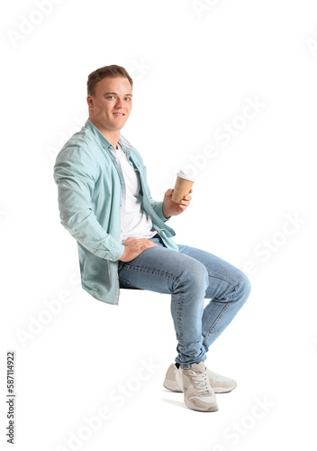 Young man with cup of coffee sitting in chair on white background