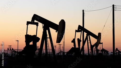 The sun rises behind oil pumps in California