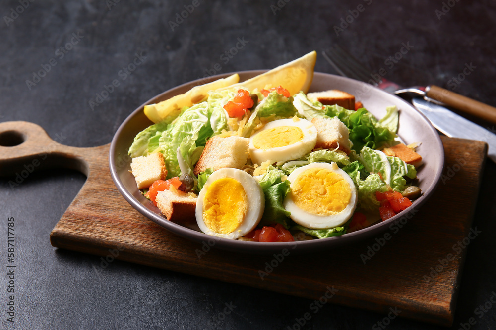 Plate of delicious salad with boiled eggs and salmon on black grunge background Plate of delicious salad with boiled eggs and salmon on black grunge background