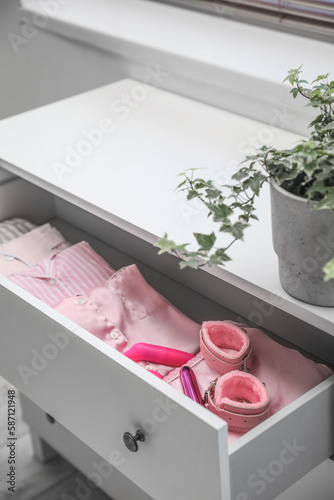 Open drawer with sex toys and pajamas in bedroom, closeup