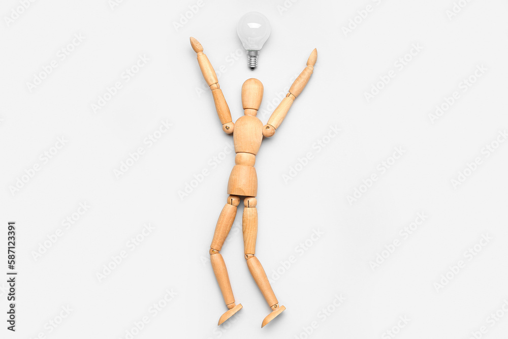 Wooden mannequin with light bulb on light background. Insight concept Wooden mannequin with light bulb on light background. Insight concept