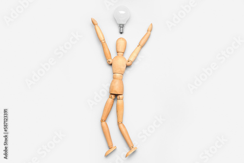 Wooden mannequin with light bulb on light background. Insight concept