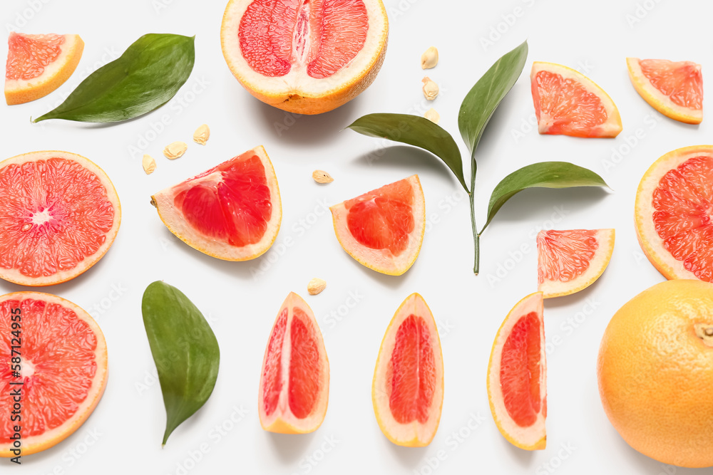 Composition with pieces of ripe grapefruit, seeds and plant leaves on white background Composition with pieces of ripe grapefruit, seeds and plant leaves on white background