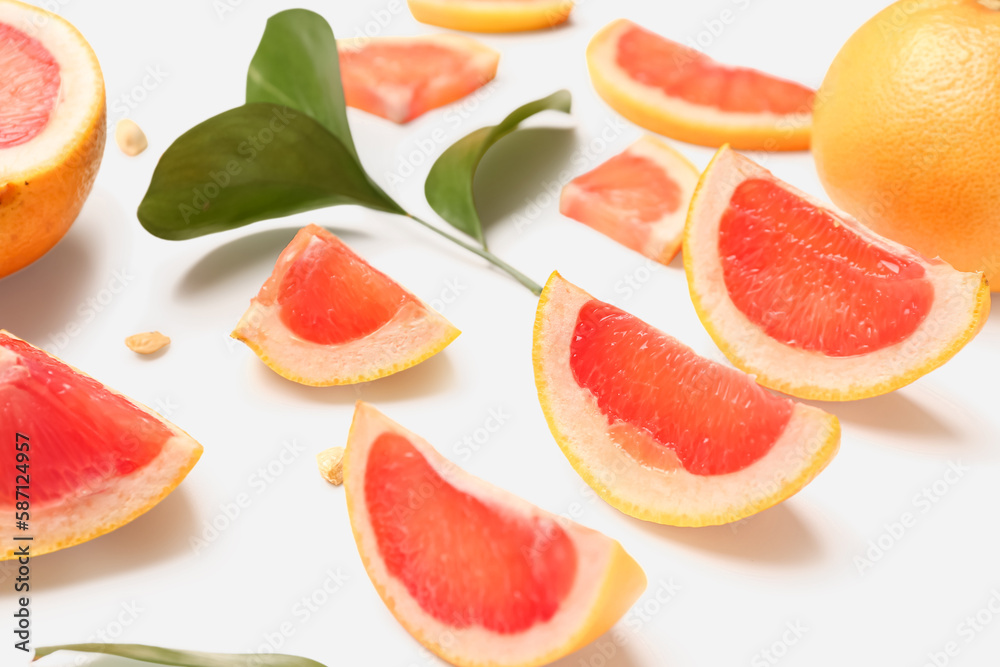 Composition with pieces of ripe grapefruit, seeds and plant leaves on white background, closeup Composition with pieces of ripe grapefruit, seeds and plant leaves on white background, closeup