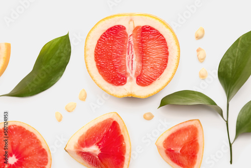 Composition with pieces of ripe grapefruit, seeds and plant leaves on white background, closeup