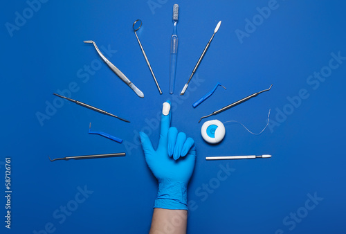 Dentist in medical glove with tools on blue background