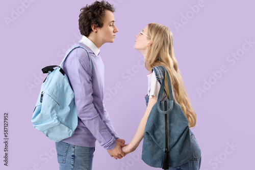 Teenage couple holding hands on lilac background