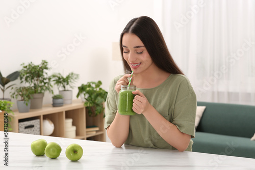 Beautiful young woman drinking delicious smoothie at home