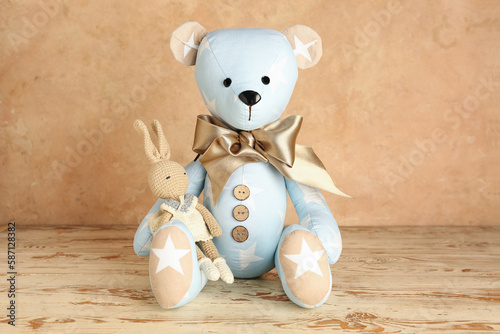 Toy bear and bunny on table near grunge wall