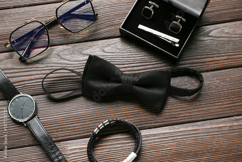 Set of stylish male accessories with bow tie on wooden background, closeup