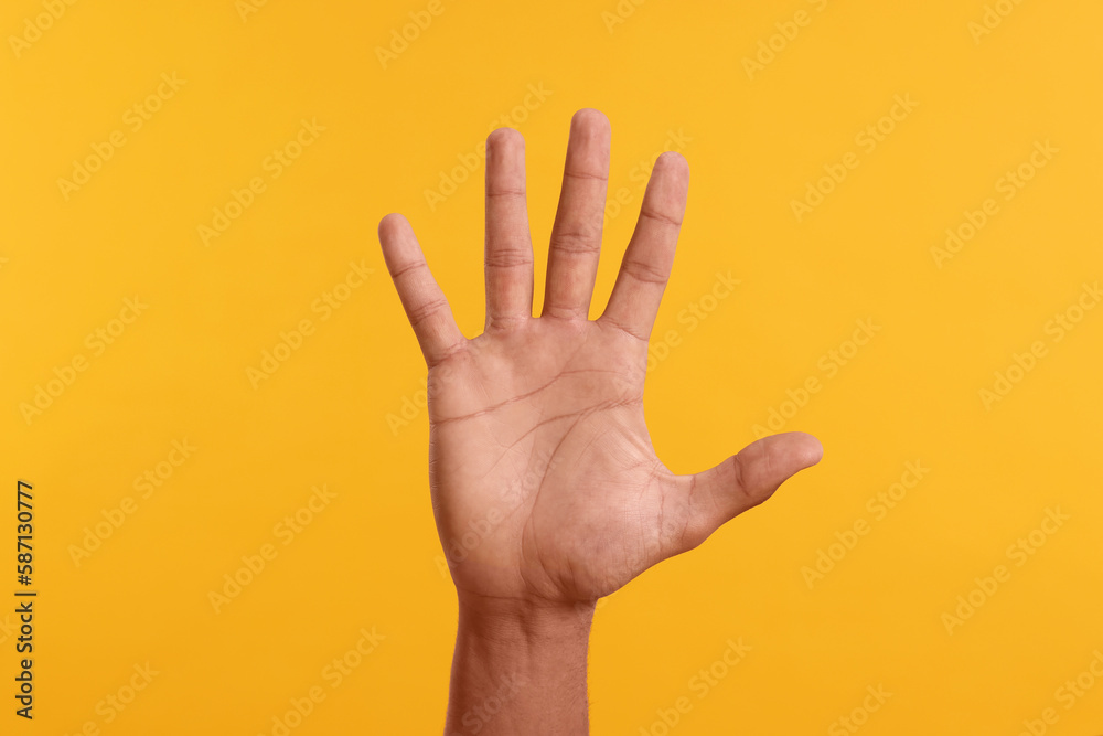 Man giving high five on yellow background, closeup of hand - obrazy, fototapety, plakaty 
