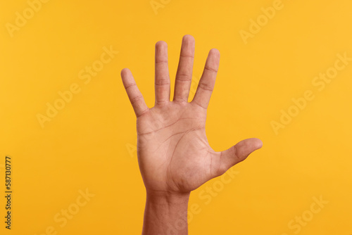Man giving high five on yellow background, closeup of hand photo