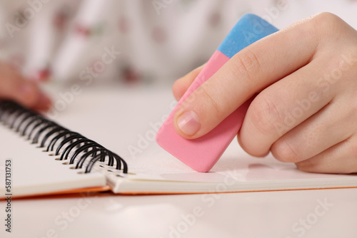 Photos Girl using eraser at white desk, closeup