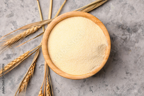 Bowl with raw semolina on grunge background