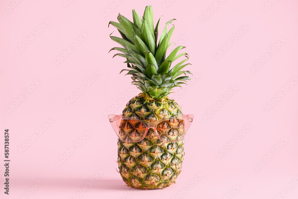 Fresh ripe pineapple with sunglasses on pink background